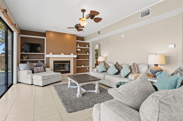 living room with ceiling fan, visible vents, light tile patterned flooring, and a tile fireplace