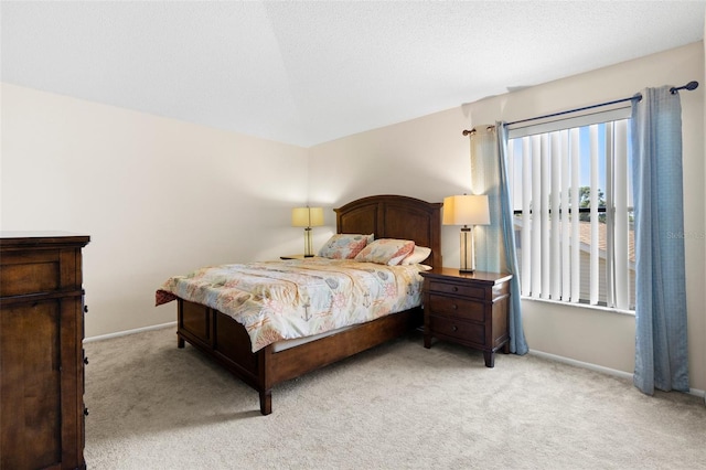bedroom featuring baseboards, light carpet, and a textured ceiling