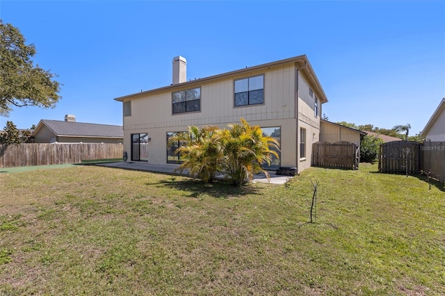 rear view of property featuring a fenced backyard, a patio area, a chimney, and a yard