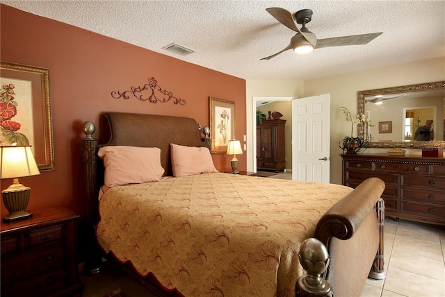 bedroom featuring visible vents, ceiling fan, light tile patterned floors, and a textured ceiling