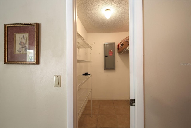 interior space featuring a textured ceiling, baseboards, tile patterned flooring, and electric panel
