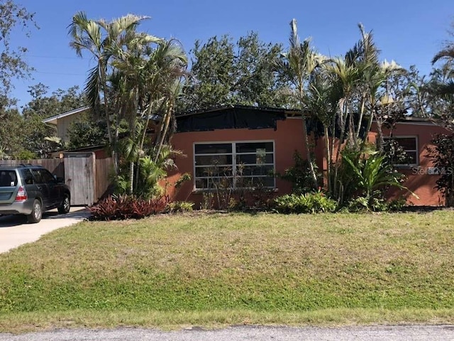 1465 Fundy Rd, Venice, FL 34293 - view of front facade featuring stucco siding, a front yard, and fence