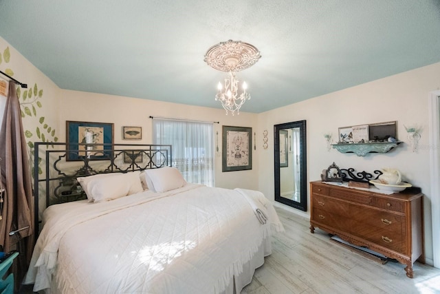 bedroom featuring wood finished floors, a chandelier, and access to exterior