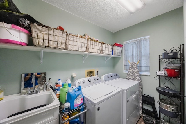 clothes washing area featuring a sink, a textured ceiling, laundry area, and independent washer and dryer