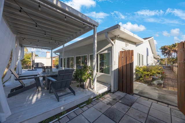 view of patio featuring fence, a deck, and outdoor dining space