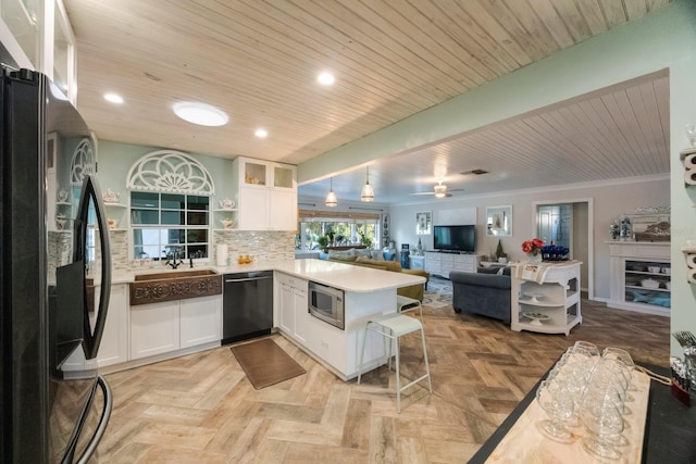 kitchen with white cabinets, black appliances, a peninsula, and open floor plan