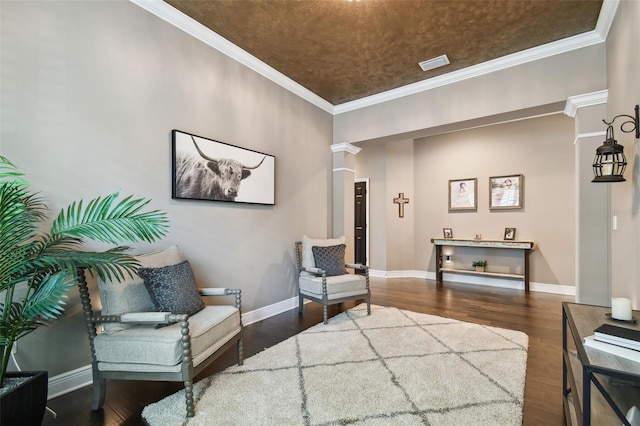 living area with wood finished floors, visible vents, ornate columns, baseboards, and ornamental molding