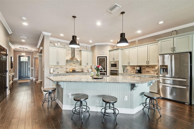 kitchen featuring a spacious island, visible vents, light stone counters, appliances with stainless steel finishes, and wall chimney exhaust hood