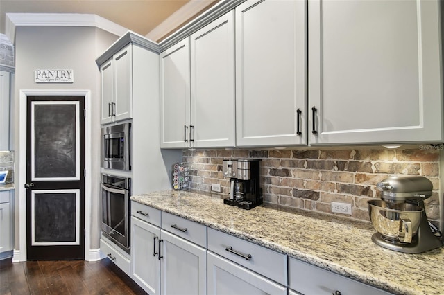 kitchen with dark wood-style floors, light stone countertops, stainless steel appliances, crown molding, and tasteful backsplash