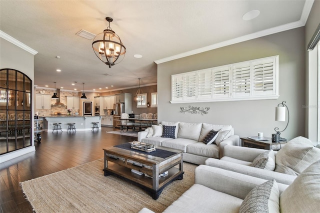 living room featuring dark wood-type flooring, an inviting chandelier, and crown molding