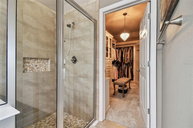 bathroom with a walk in closet, a chandelier, and a shower stall