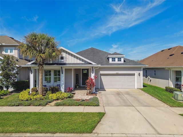 view of front of house featuring a front lawn, a garage, driveway, and a shingled roof