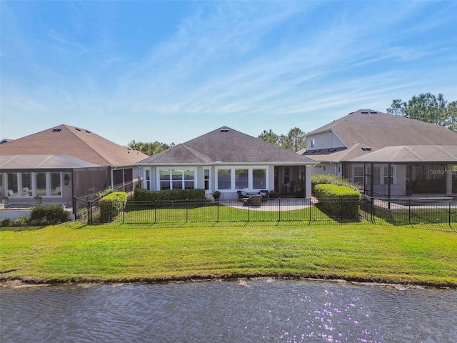 back of property featuring a water view, a lawn, and a fenced backyard