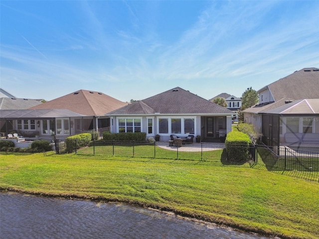 rear view of house featuring a sunroom, a fenced backyard, a lawn, and a water view