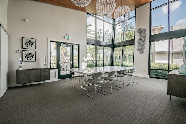 carpeted dining area featuring floor to ceiling windows, baseboards, and a towering ceiling