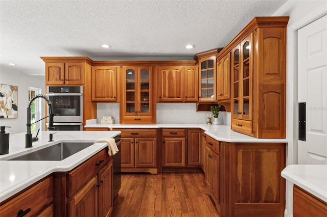 20315 Mid Ct, Lutz, FL 33558 - kitchen featuring brown cabinetry, light countertops, dark wood-style floors, and glass insert cabinets