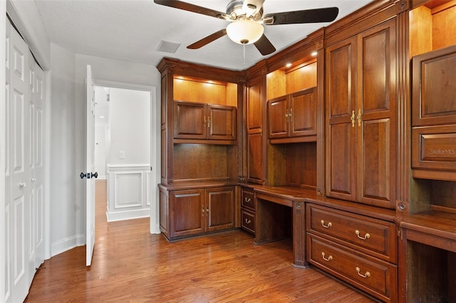 20315 Mid Ct, Lutz, FL 33558 - unfurnished office with ceiling fan, built in desk, wood finished floors, a wainscoted wall, and a decorative wall