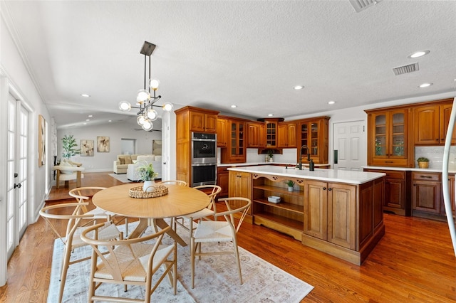 20315 Mid Ct, Lutz, FL 33558 - kitchen with a kitchen island with sink, visible vents, brown cabinets, light countertops, and double oven