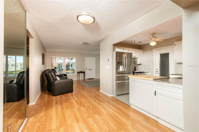 9870 36th Way N, Pinellas Park, FL 33782 - kitchen with stainless steel fridge with ice dispenser, white cabinetry, light wood-style flooring, open floor plan, and a textured ceiling