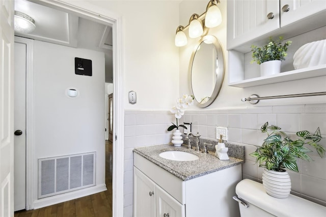 3818 W San Miguel St, Tampa, FL 33629 - bathroom featuring tile walls, visible vents, toilet, wood finished floors, and vanity