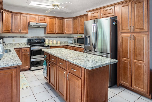 kitchen with backsplash, a center island, under cabinet range hood, brown cabinets, and stainless steel appliances