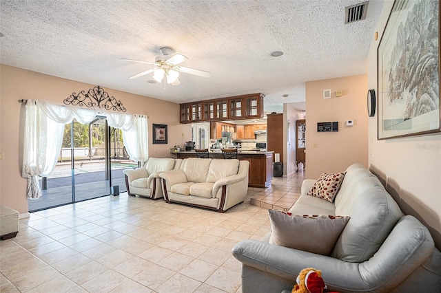 living area featuring visible vents, a textured ceiling, ceiling fan, and light tile patterned flooring