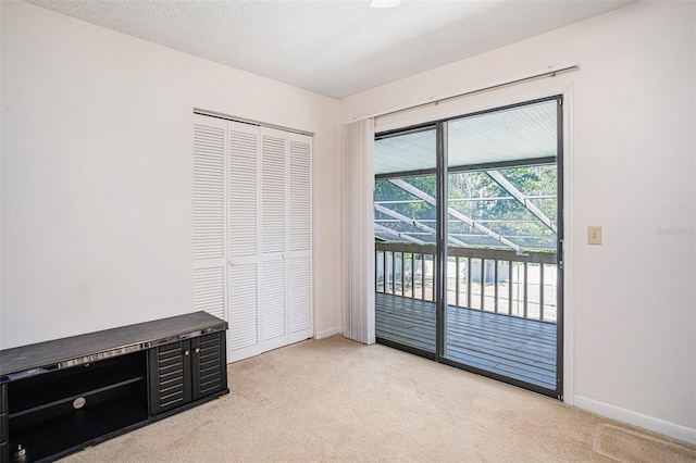 bedroom with baseboards, a closet, a textured ceiling, access to outside, and light colored carpet