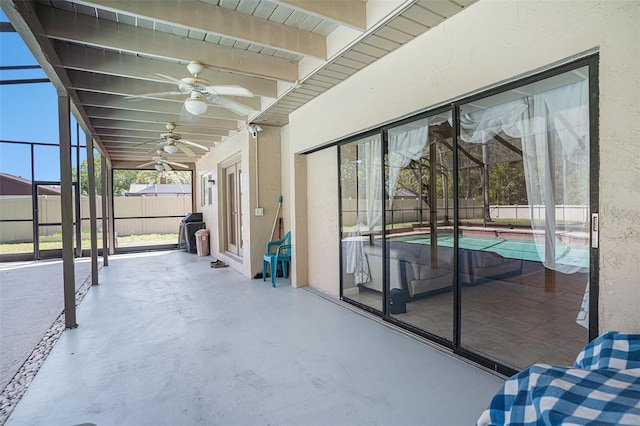 unfurnished sunroom featuring beamed ceiling and ceiling fan