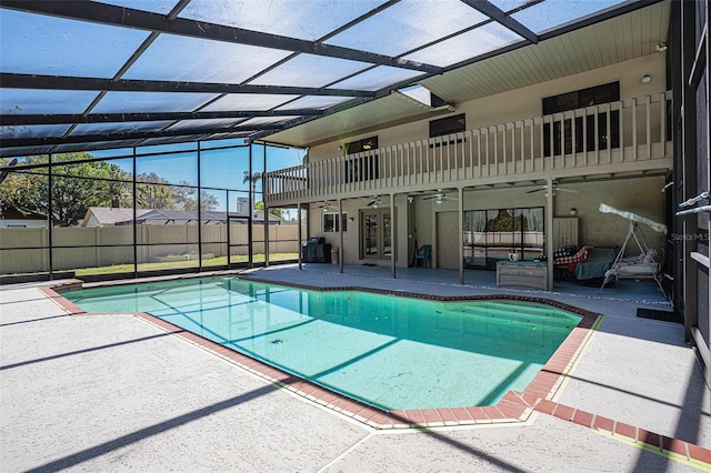 view of swimming pool featuring a ceiling fan, fence, french doors, a lanai, and a patio area