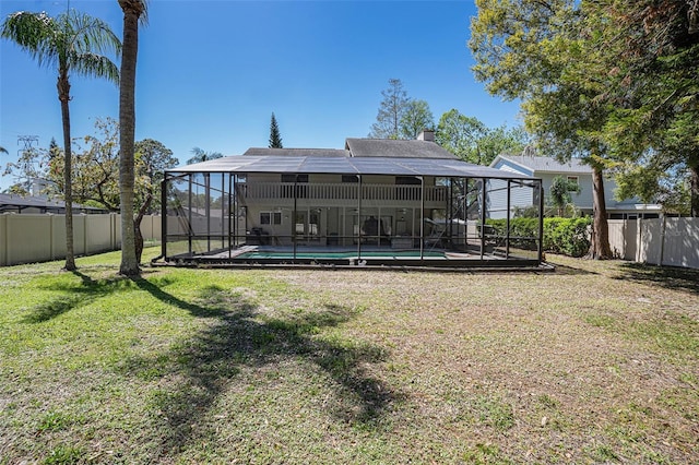 back of property featuring a lanai, a fenced in pool, a lawn, and a fenced backyard