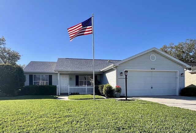 ranch-style house with a front yard, concrete driveway, an attached garage, and roof with shingles