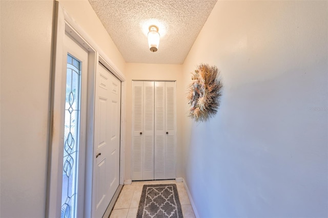 entryway featuring light tile patterned floors, a textured ceiling, and baseboards