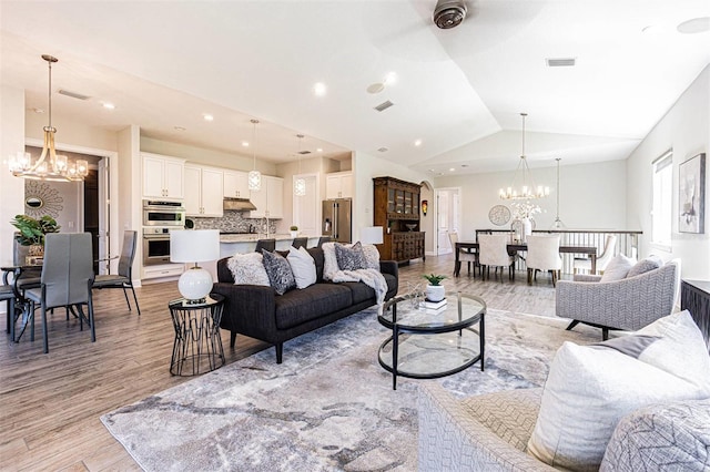 16 Franklin Ct S Unit A, Saint Petersburg, FL 33711 - living area featuring vaulted ceiling, ceiling fan with notable chandelier, light wood-type flooring, and visible vents