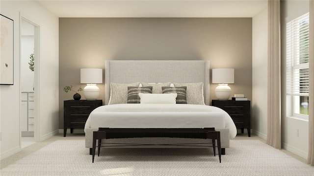 bedroom with ensuite bath, light colored carpet, and baseboards
