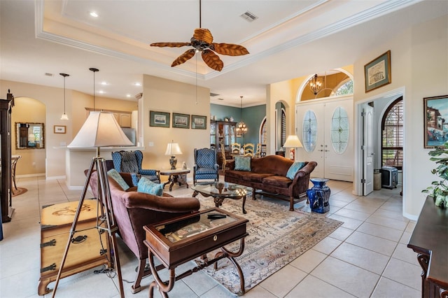 living room featuring light tile patterned flooring, arched walkways, a tray ceiling, and crown molding