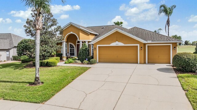 view of front of property with concrete driveway, stucco siding, an attached garage, and a front lawn
