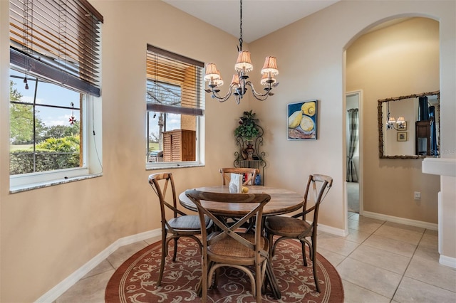 dining space featuring baseboards, arched walkways, tile patterned flooring, and an inviting chandelier
