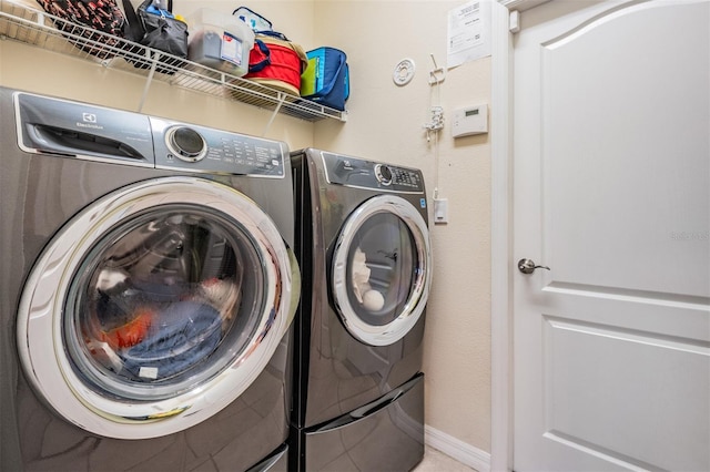 clothes washing area featuring independent washer and dryer, laundry area, and baseboards