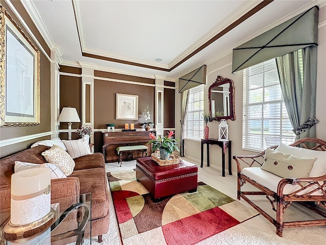carpeted living room featuring a raised ceiling, ornamental molding, and decorative columns