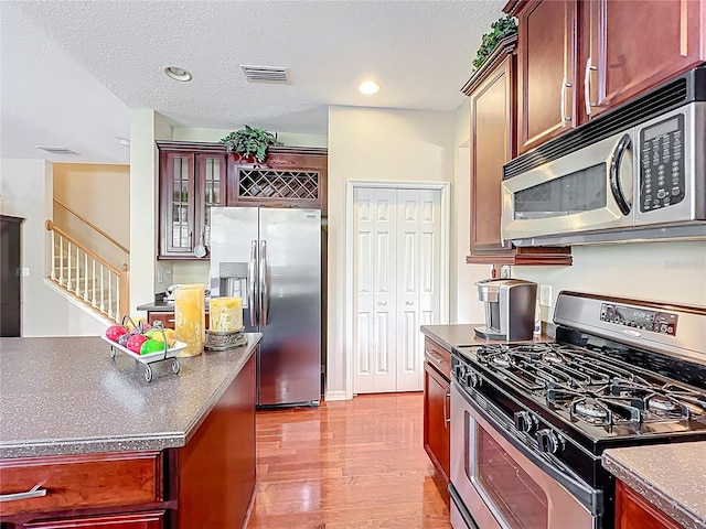 kitchen featuring dark countertops, wood finished floors, visible vents, and stainless steel appliances