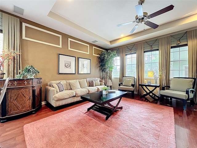 living room featuring wood finished floors, visible vents, and a ceiling fan