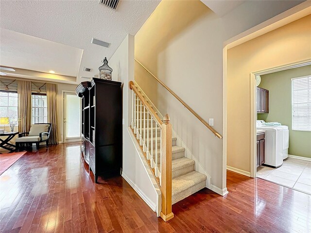 staircase with washing machine and dryer, hardwood / wood-style floors, visible vents, and a wealth of natural light