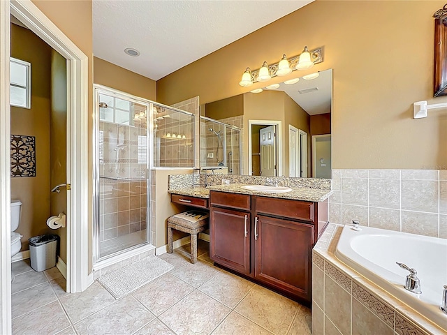 bathroom featuring tile patterned flooring, a bath, toilet, and a stall shower