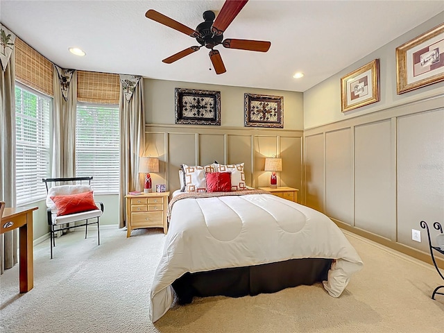 bedroom featuring a decorative wall, a ceiling fan, a wainscoted wall, and carpet floors