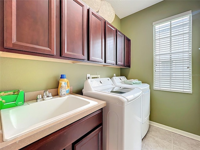 laundry room featuring a sink, light tile patterned flooring, cabinet space, baseboards, and independent washer and dryer
