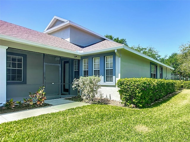 property entrance featuring stucco siding, roof with shingles, and a yard