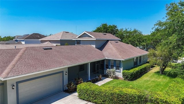 multi unit property with a shingled roof, a front lawn, concrete driveway, stucco siding, and a garage