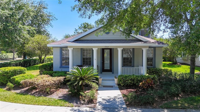 bungalow-style house with a porch, stucco siding, and a shingled roof