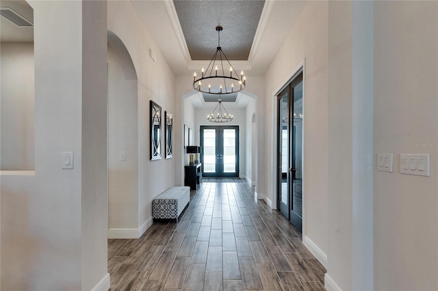 corridor with arched walkways, french doors, a notable chandelier, and wood finish floors