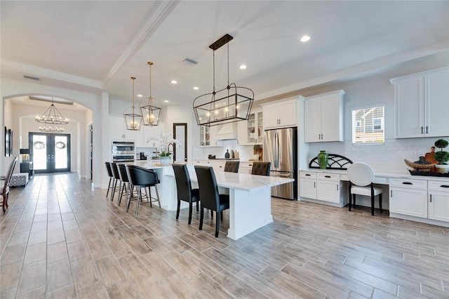 kitchen with arched walkways, decorative backsplash, a breakfast bar area, and appliances with stainless steel finishes